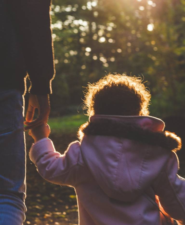 A foster parent holds the hand of a newly adopted child as they walk through a Durham County park.